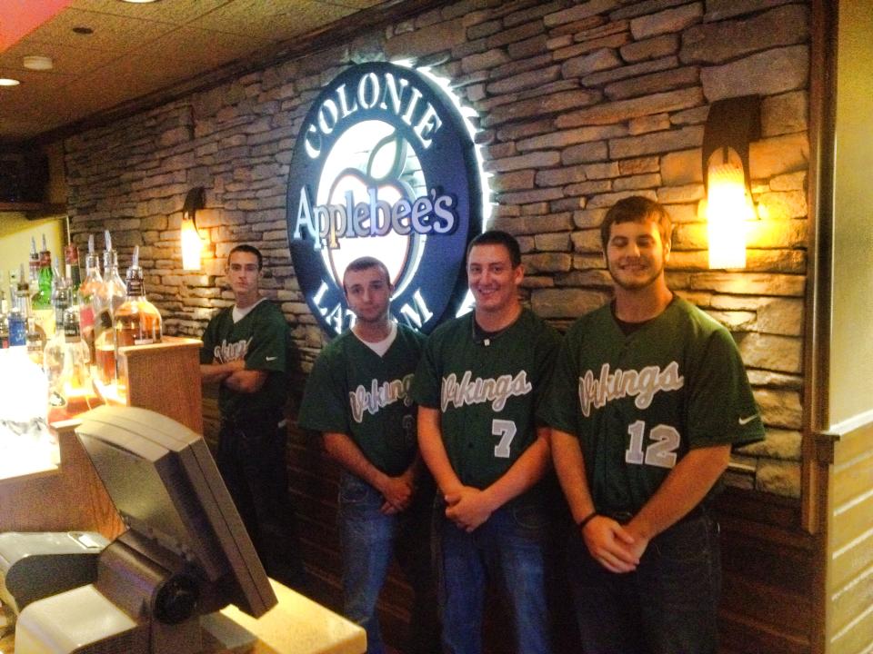 Hudson Valley Community College baseball team members in team uniform jerseys stand inside an Applebees Restauarant.