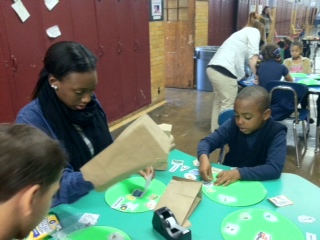 Monroe Community College student working with a second grade student at a craft table at the World of Inquiry School