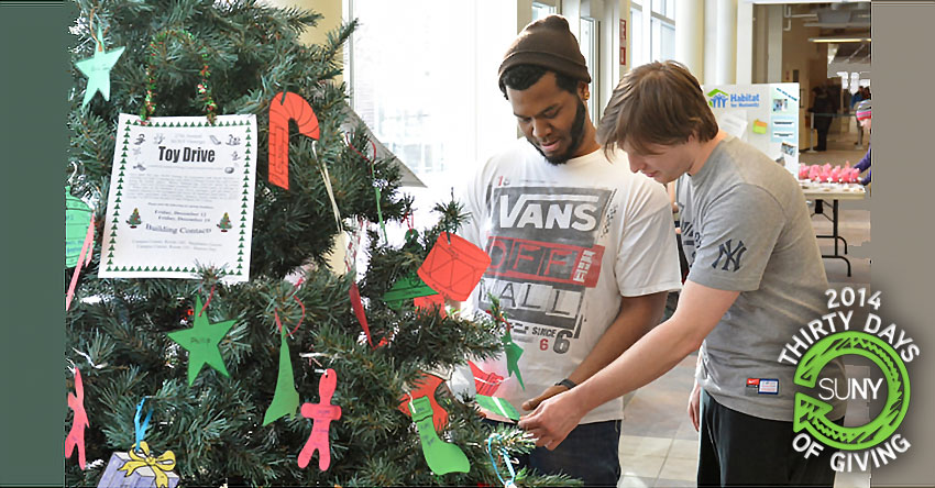 Oswego students pick paper stockings off of a tree for toy drive