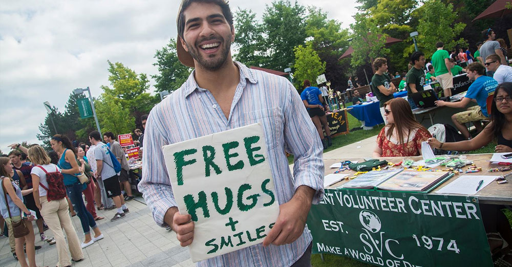 One student looks to spread joy around campus with a sign saying Free Hugs and Smiles..