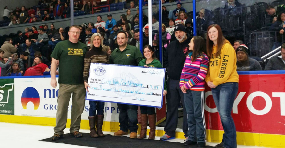 Oswego students present a check to Clear Path for Veterans at an Oswego hockey game.