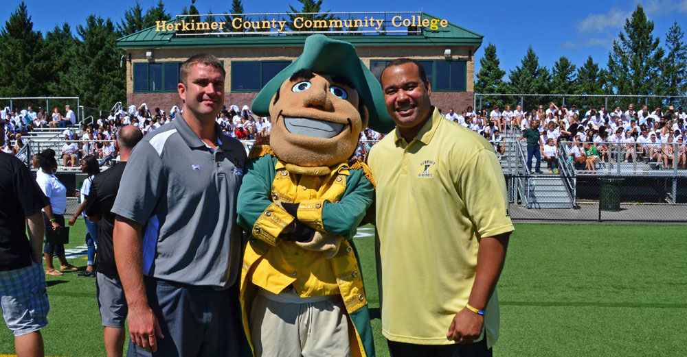 Dartray Belk with mascot and football coach at Herkimer Community College football field.