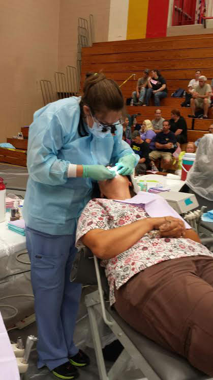 Farmingdale State student Kaitlyn Rostron gives a dental checkup to a patient in a gym.