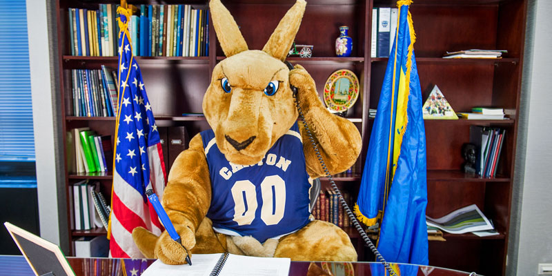 SUNY Canton mascot Roody Roo works at president's desk. 