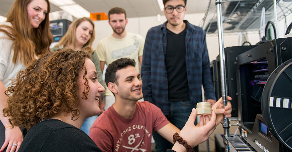 SUNY New Paltz engineering students hold a 3D printed object that just came out of a printer.