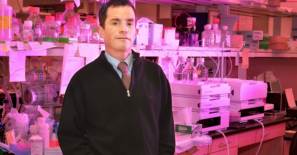 Upstate Medical University professor William Kerr stands in front of medical lab shelves.