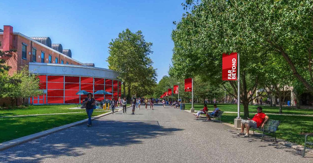 Walkway on Stony Brook University campus with red 'Far Beyond' banners hanging on light poles.