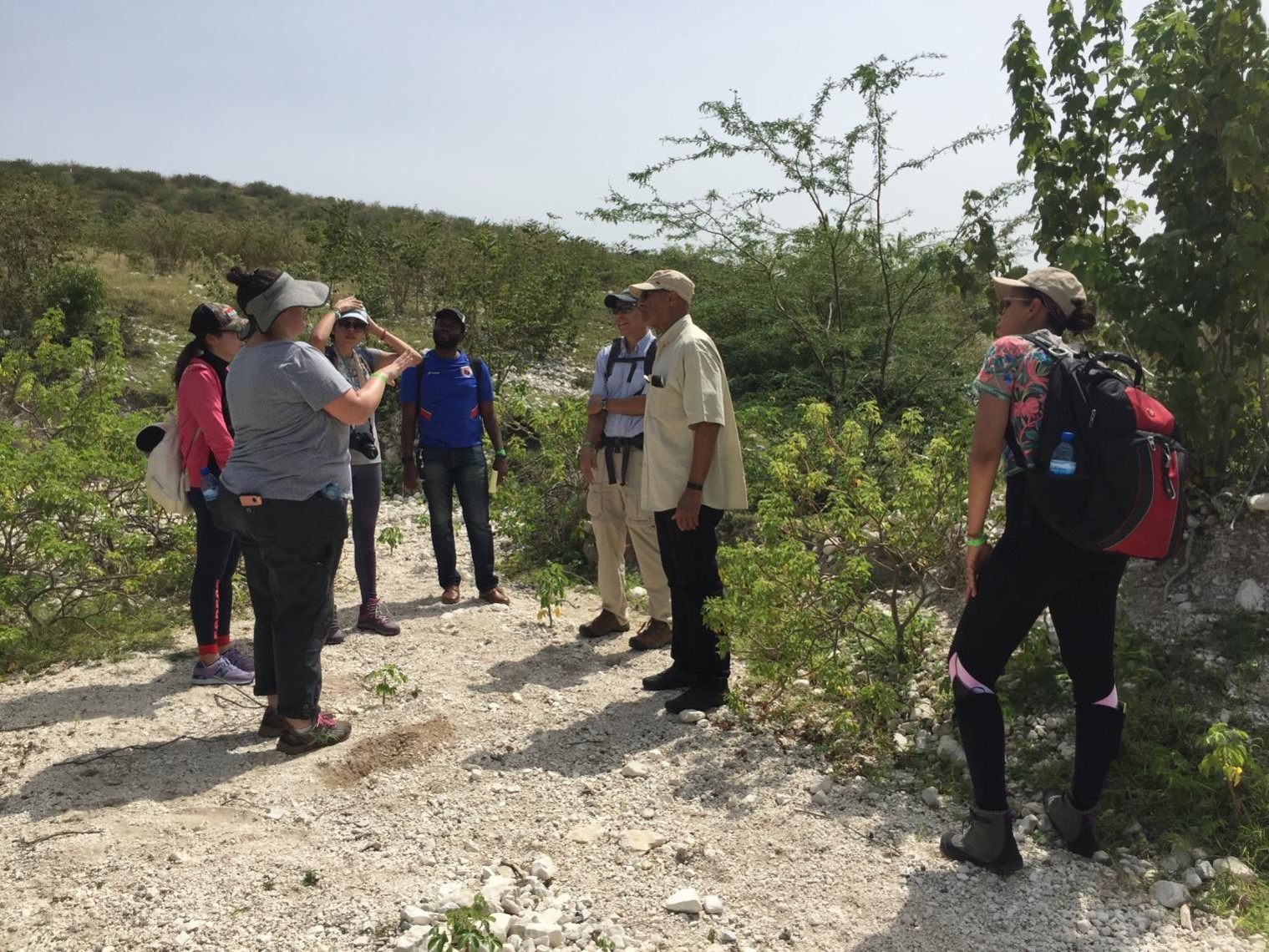 Graduate students from SUNY ESF stand on a gravel path talking with colleague Professor Emanuel Carter in Haiti.