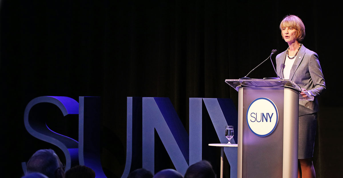 Chancellor Kristina Johnson delivers the 2018 State of the University System address behind a SUNY podium.