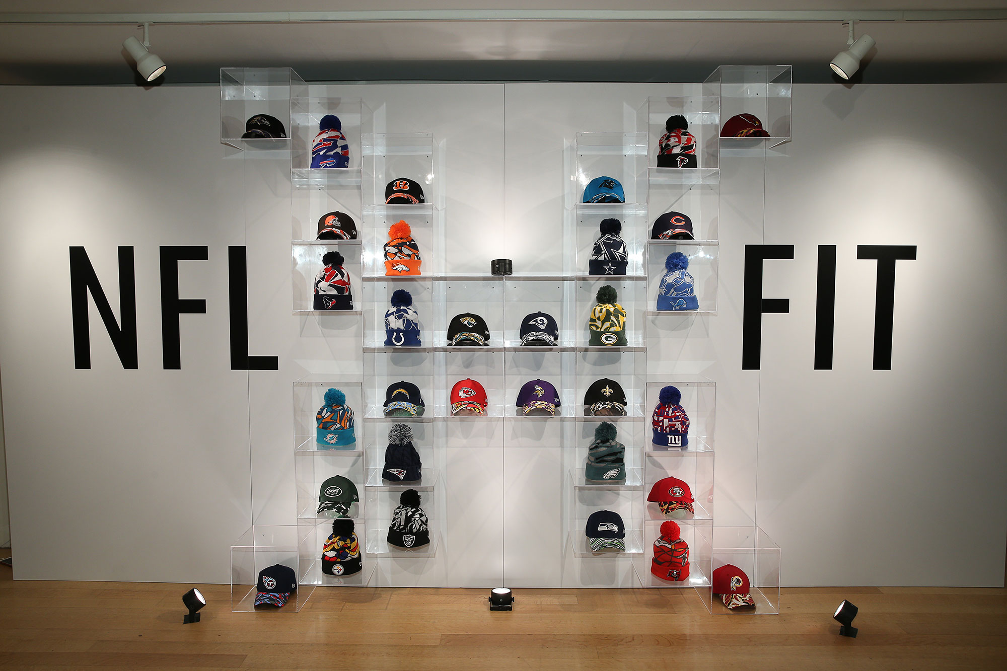 Hats of NFL teams set up in cases making an X to form NFL xFIT display.
