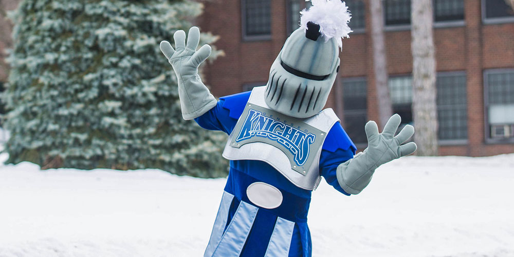 SUNY Geneseo's mascot Victor E Knight outside in front of the Suess spruce tree.