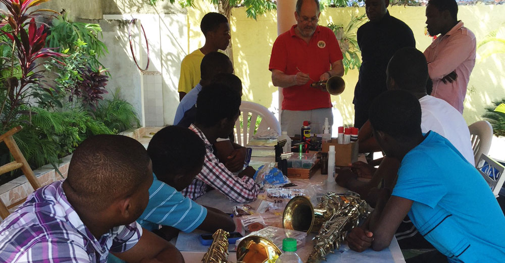 Bill Cole shows Hatian locals the details of a horn as musical instrument.