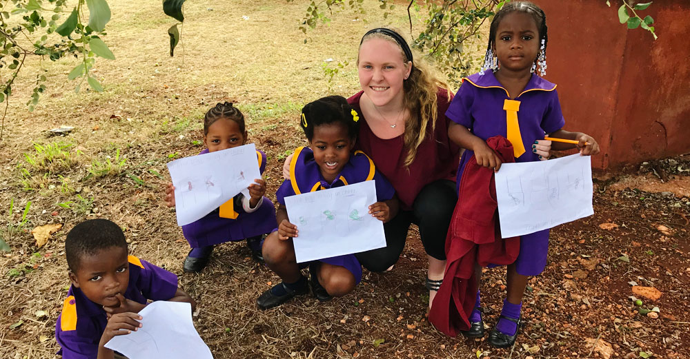 Farmingdale State College student Kaitlyn Kallansrude outside with school children in Jamaica.