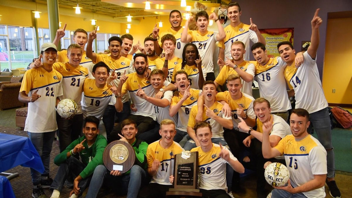 Genesee Community College men's soccer team poses in celebration with the NJCAA national championship plaque.