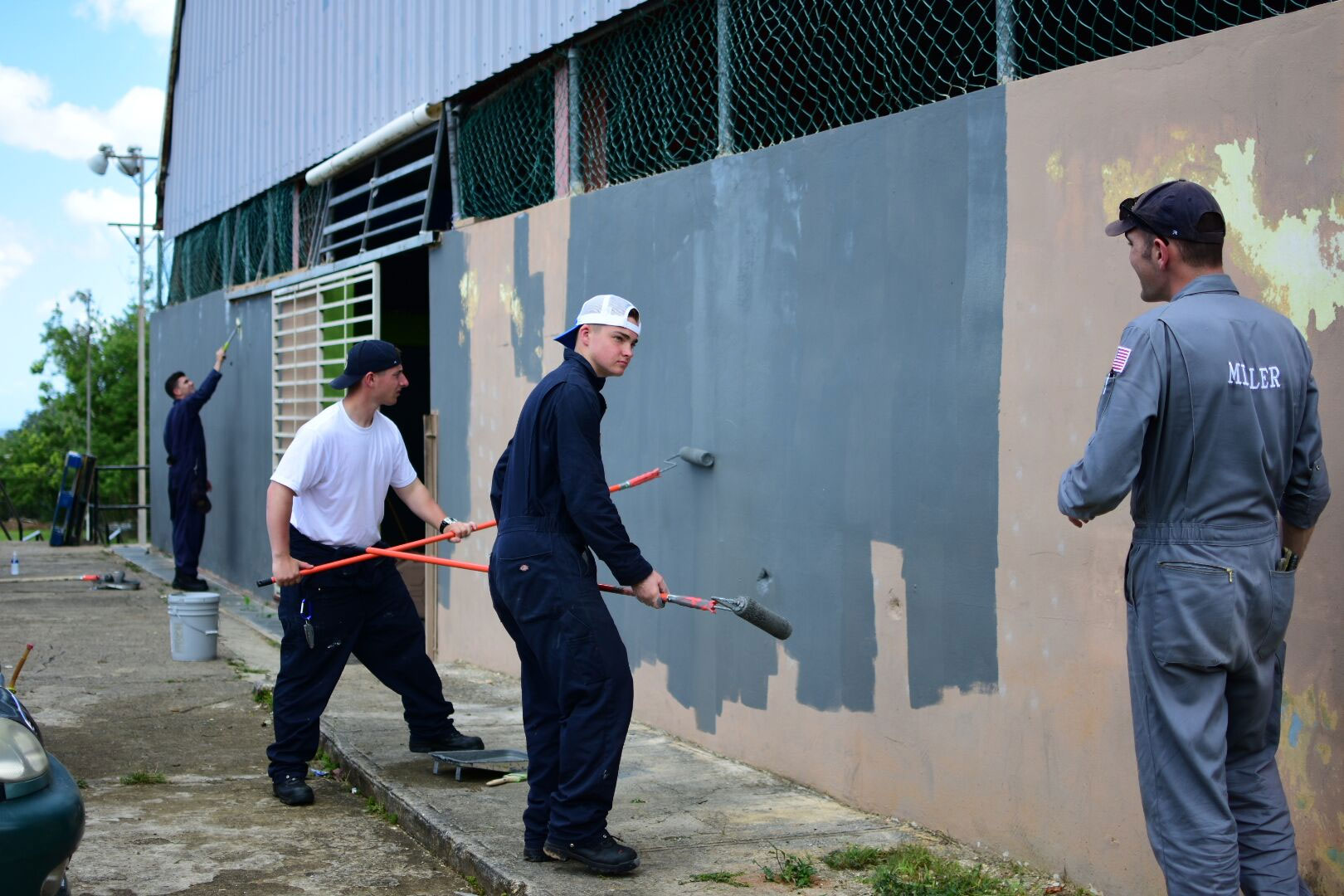 SUNY Maritime College students paint a building exterior in Puerto Rico.