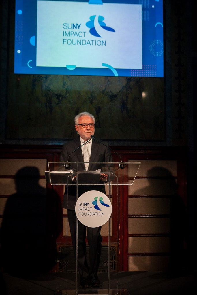 Wolf Blitzer speaks at a podium at the SUNY Impact Foundation Chancellor inauguration gala.