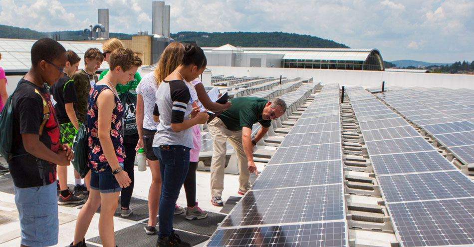 Binghamton University professor shows students a solar panel setup on a rooftop.