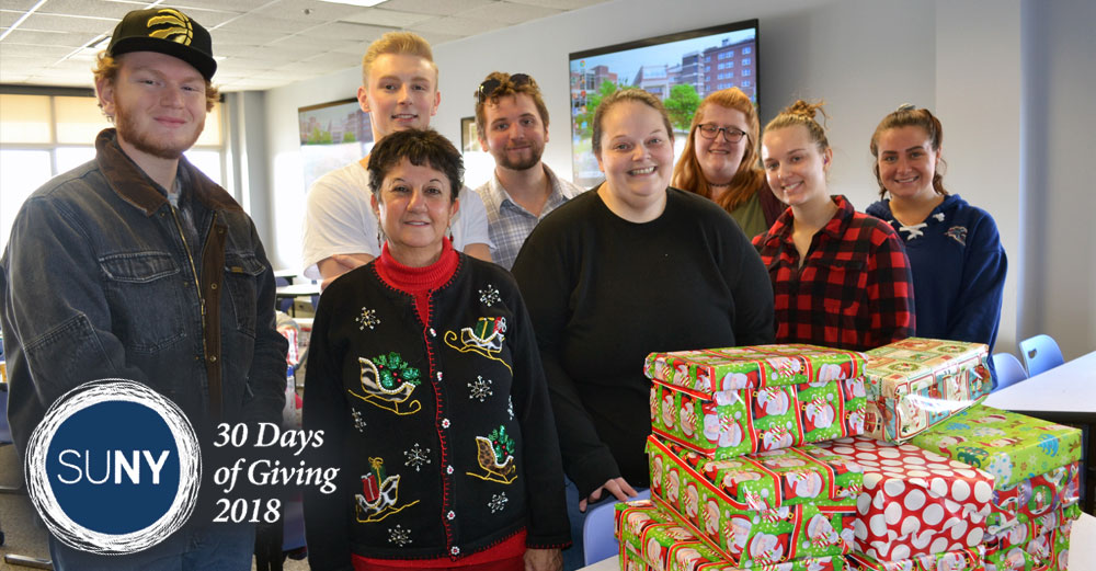 Schenectady County Community College students and staff at a table that has piles of wrapped presents.