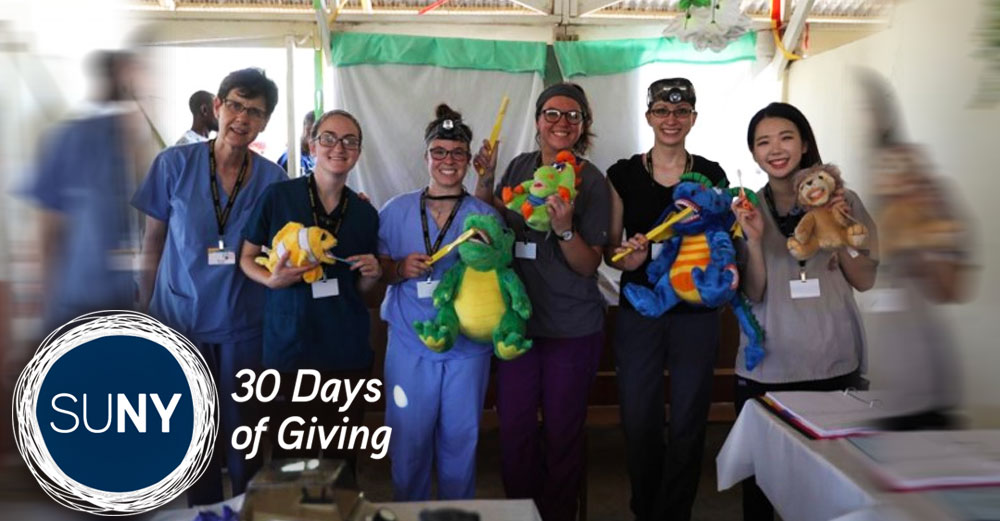 SUNY Broome dental students pose with stuffed animals in a medical tent.