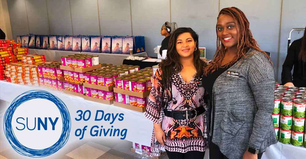 2 female Westchester Community College students stand in front of a large table of donated food items.
