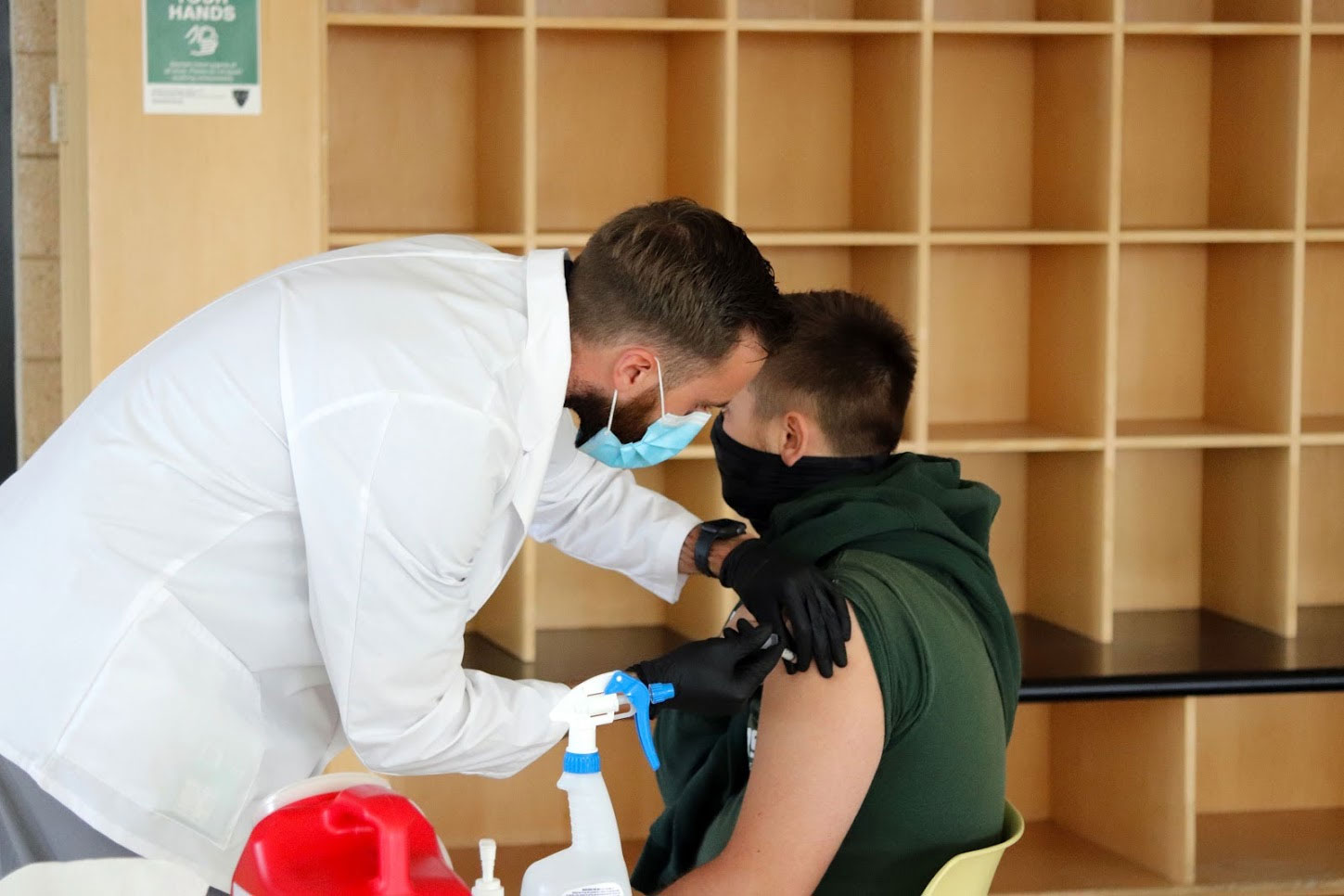 A male student receives a flu shot in the arm from a doctor in white coat.