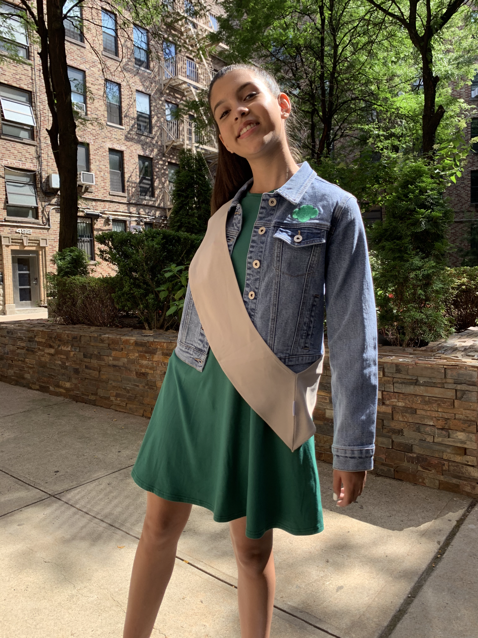 Young girl scout modeling new uniform outside on city sidewalk.