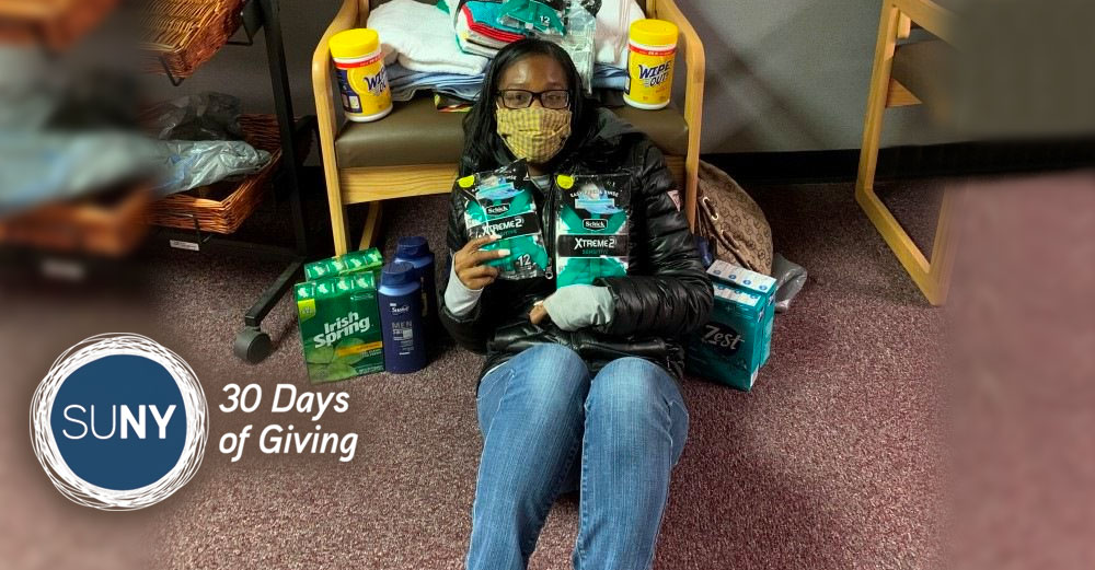 Female student sits on the ground holding various bath soaps and care items that are part of a donation effort.