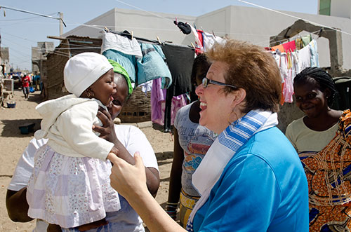 Caryl Stern smiles at an infant in a desert village