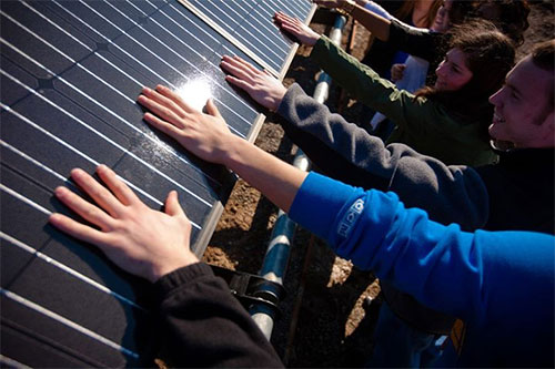 University at Buffalo solar panel with students touching it