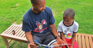 Man reading to young boy on a park bench