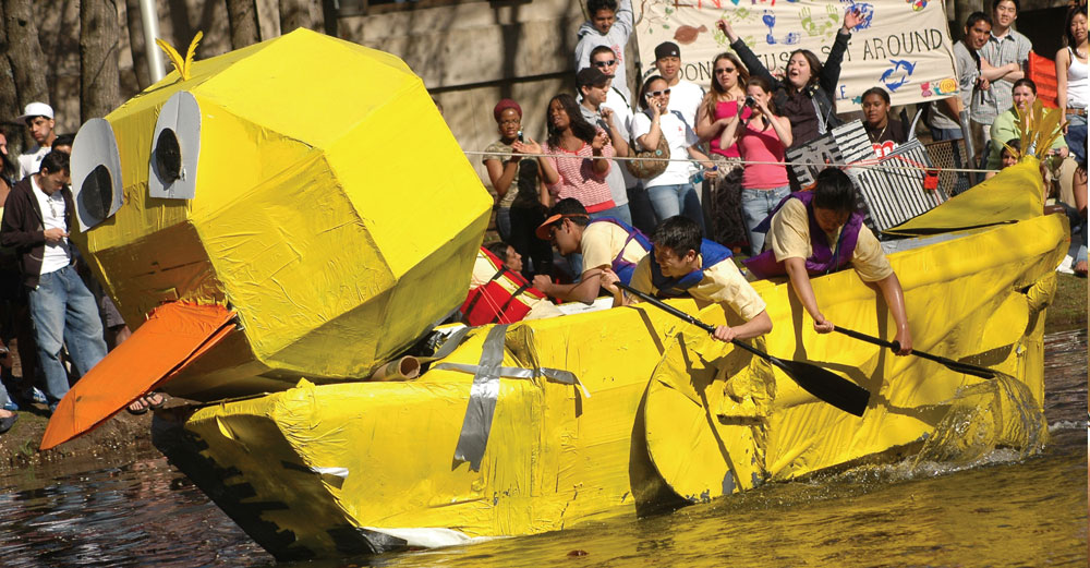 Yellow duck boat made of paper races down waterat Stony Brook Roth Pond Regatta