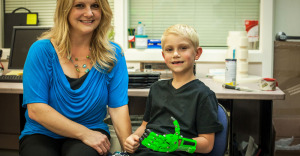 young Joey with his 3D printed glow in the dark prosthesis hand at SUNY New Paltz
