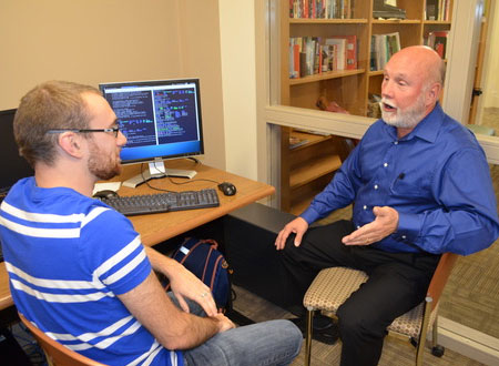 Assistant Professor Bill WIlliams from SUNY Delhi talks computer science with a student in front of computer. 