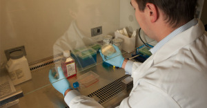 Farmingdale State professor J. Robert Coleman looks through glass at test sample in medical lab.