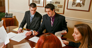 SUNY Delhi business students at a conference table in business dress.