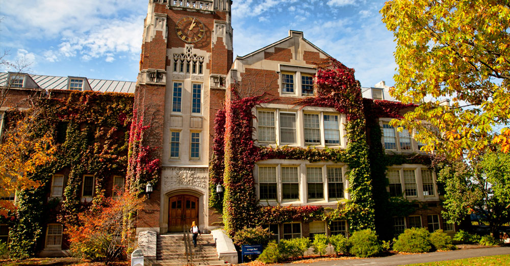 SUNY Geneseo campus building with autum leaves surrounding.