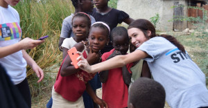 SUNY Broome female student poses for selfie with Haitian children in Haiti.