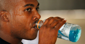 Man drink gatorade while sweating during workout.