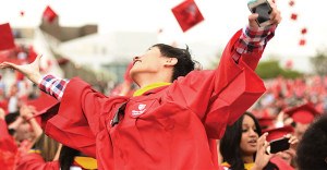 Stony Brook University graduate cheers with classmates at commencement.