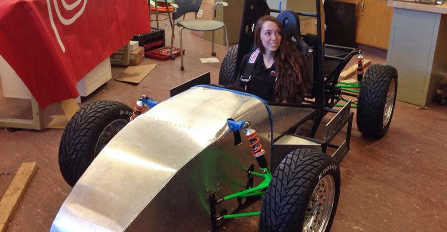 A student sits behind the wheel of the Green Machine electric car.