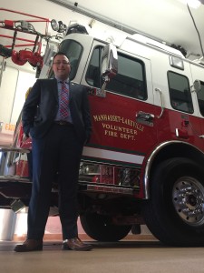Looking up at Joe Antonelli from the ground as he stands in front of fire truck cab.