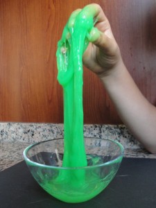 Green slime being pulled up and stretched out of a bowl. 
