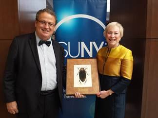 ESF President Wheeler and SUNY Chancellor Zimper stand with picture of new beetle founded at SUNY ESF.