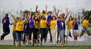 UAlbany students jump and cheer in front of school fountain