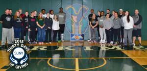 Herkimer County Community College students stand against wall for picture in gym.