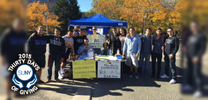 Members of a new fraternity at Stony Brook University, Pi Kappa Phi, at a canopy tent and table helping people with disabilities.