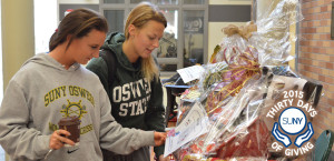 2 female Oswego students look at gift baskets on display.