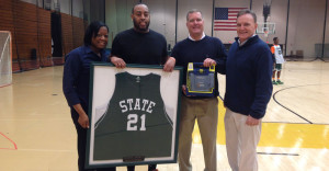 Melinda Murray and family stand on basketball court with framed jersey of Dominick Murray.