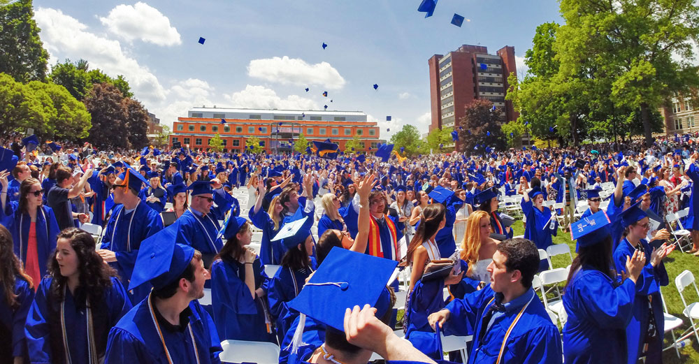 New Paltz graduates toss caps on lawn of 2015 commencement.