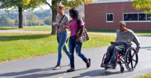 Students at Mohawk Valley Community College walk outside with student in wheelchair.